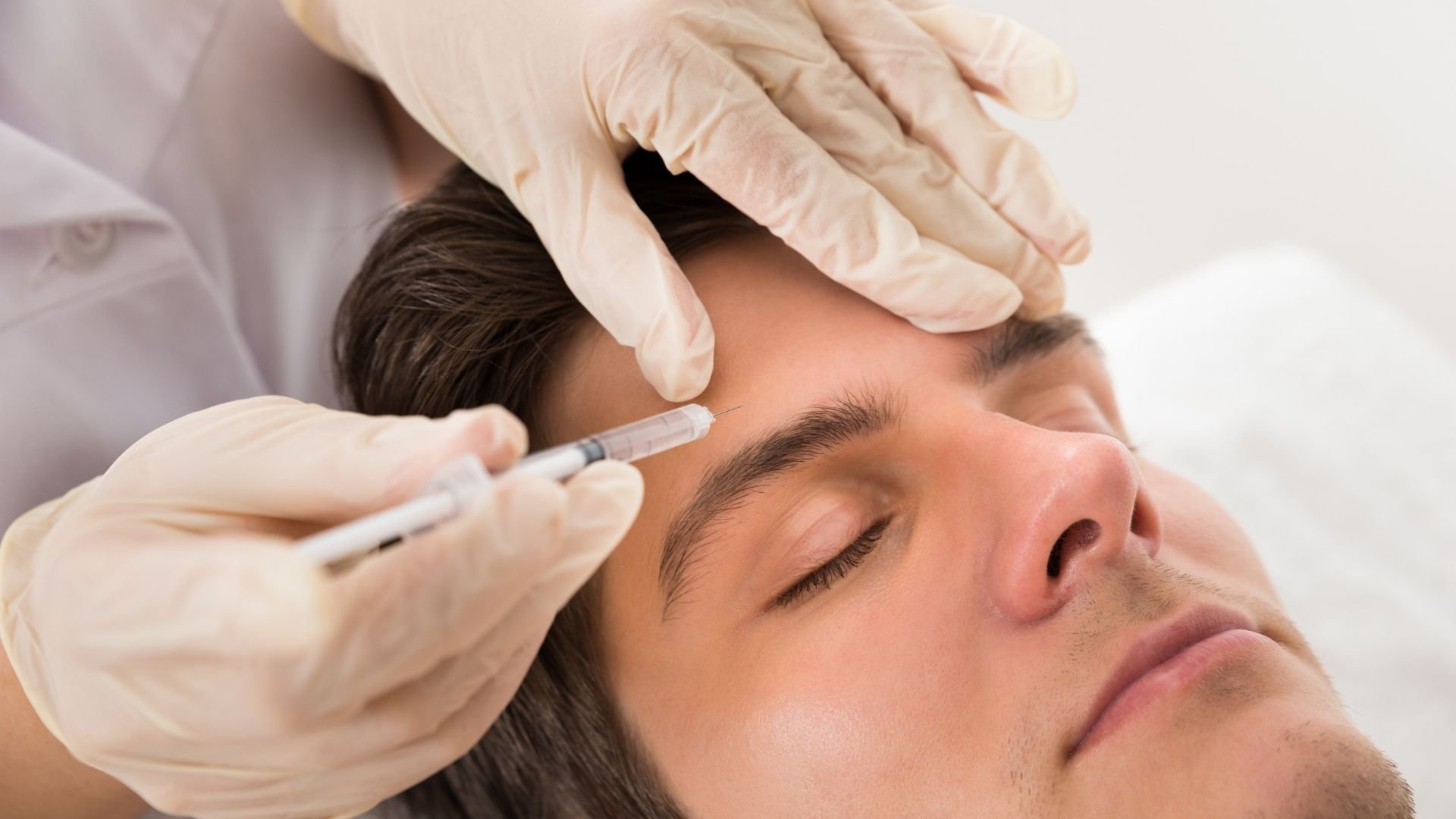 Medical professional in latex gloves administering injection to patient's forehead