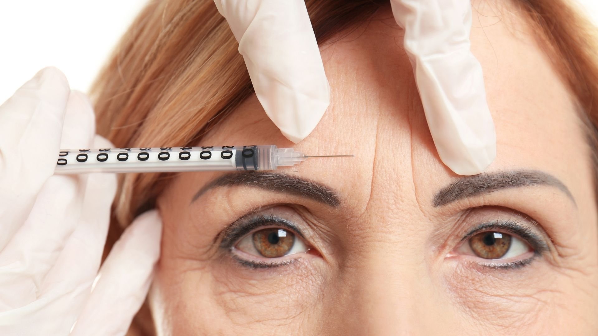 Doctor measuring forehead wrinkles with ruler during cosmetic skin examination procedure